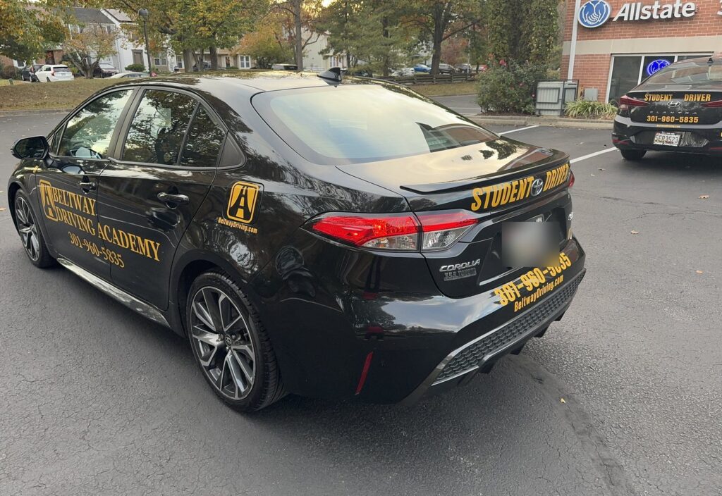 Rear three-quarter view of a Beltway Driving Academy training car marked Student Driver
